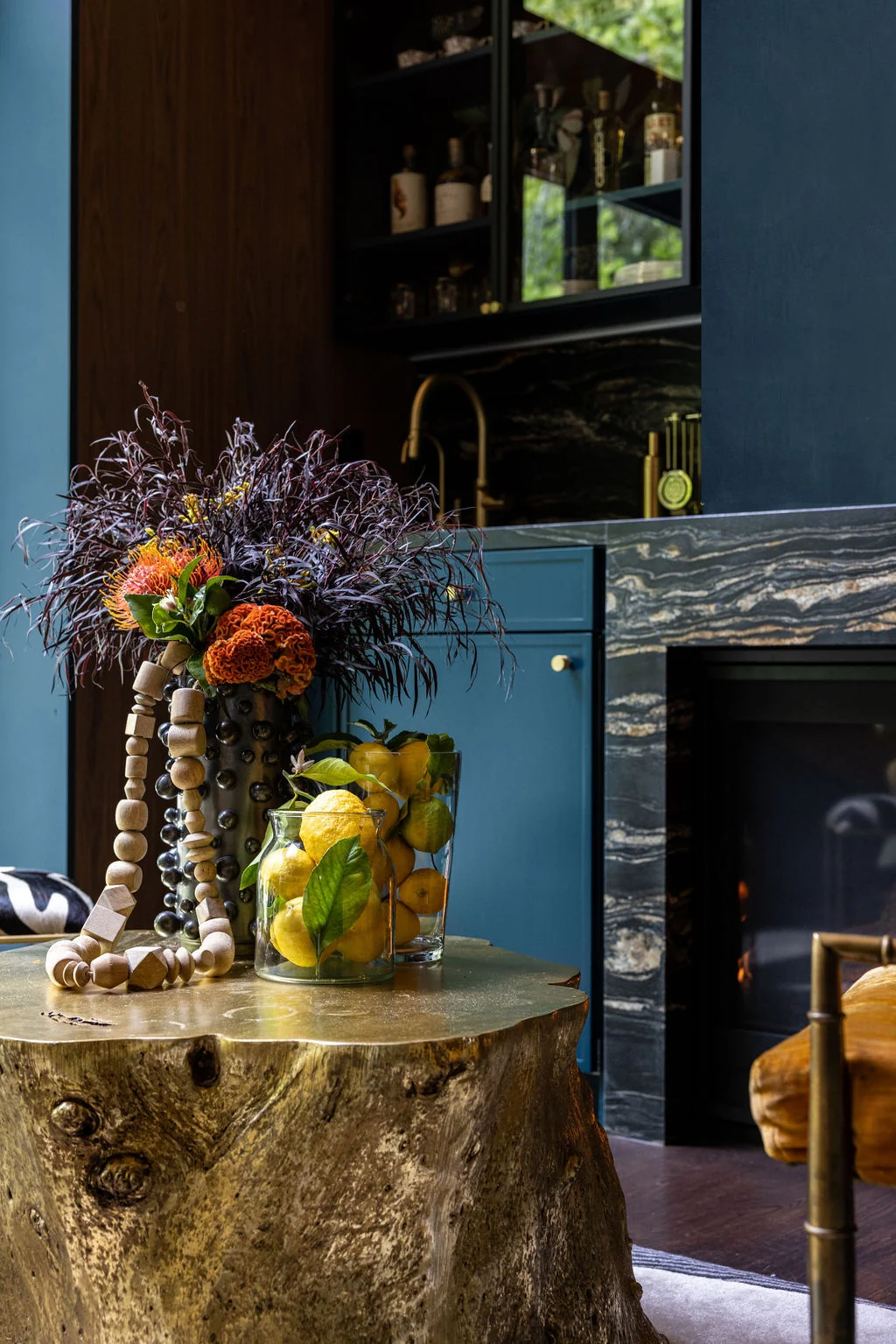 Dark blue bar with a marble counter, brass tap and a still life of flowers and lemons