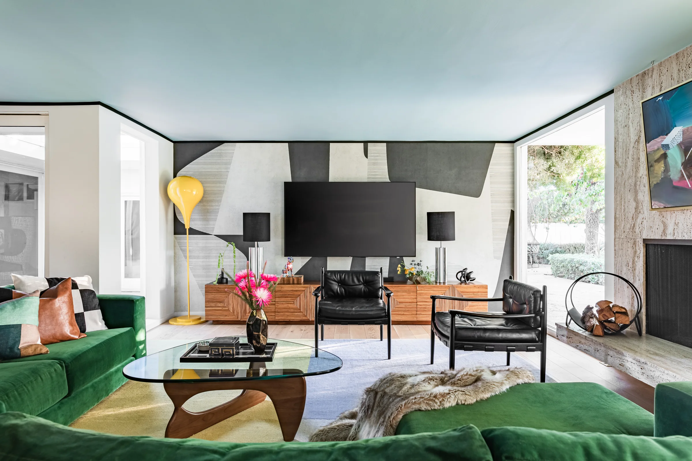 Family room with a graphic painted ceiling, emerald velvet sectional and midcentury credenzas