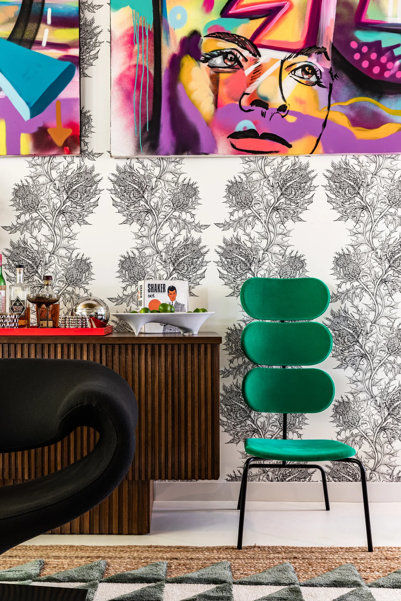 Desk vignette with graffiti-style canvases and a green ribbed chair