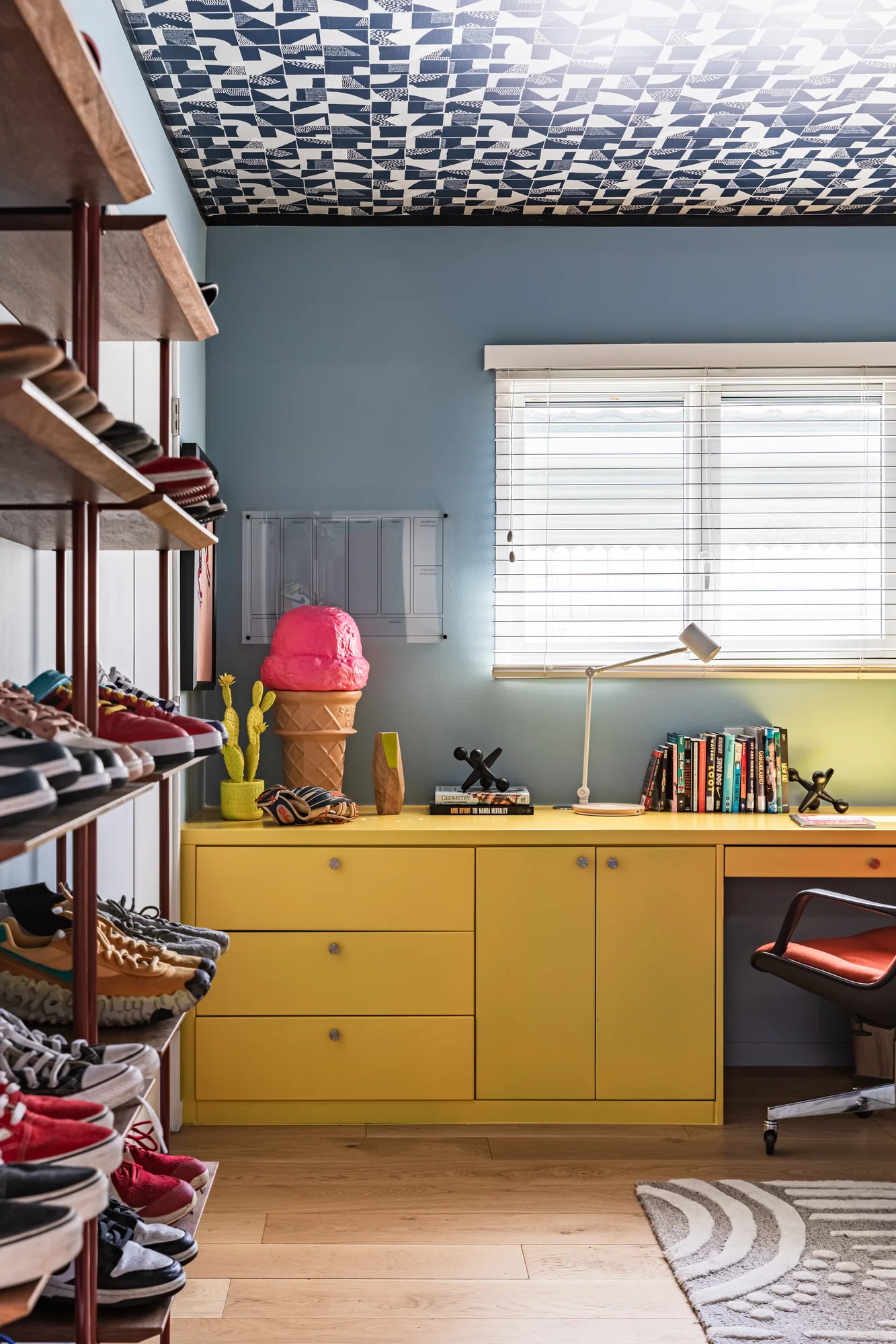 Sneaker shelving and a yellow built-in desk under a patterned ceiling