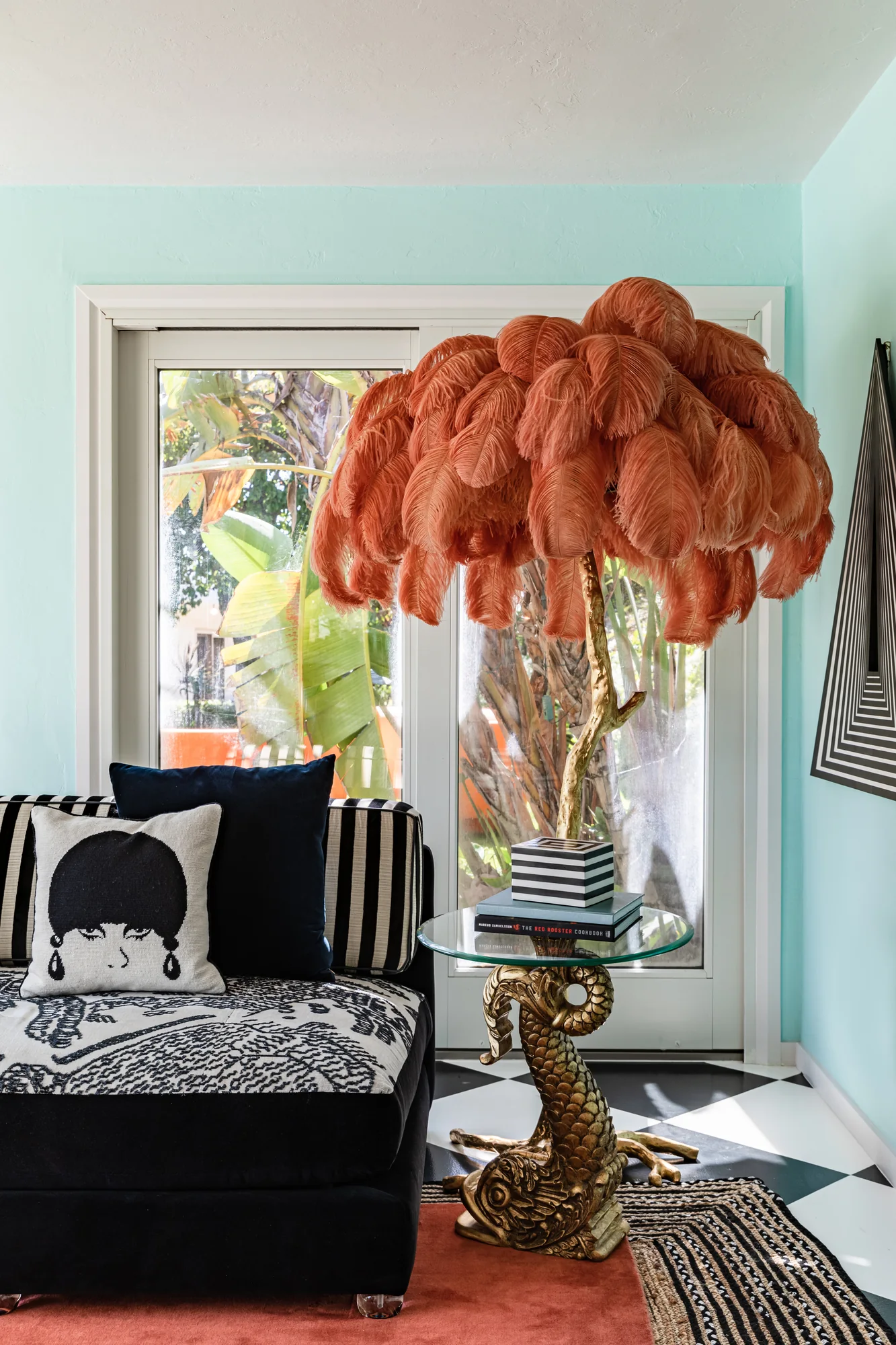 Coral ostrich-feather lamp above a black patterned daybed