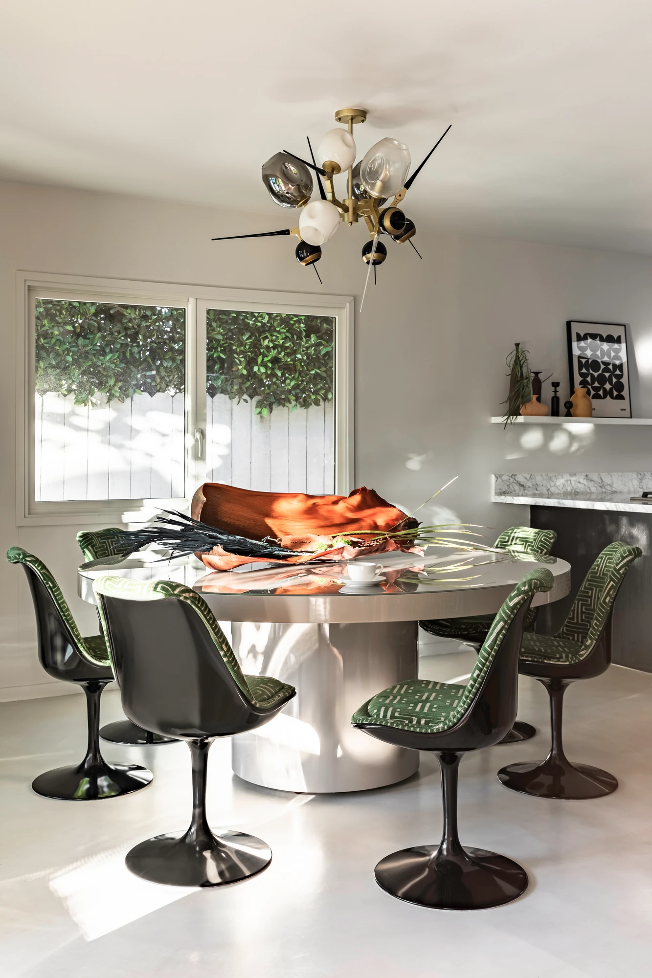 Dining room with a tulip table, green cane chairs and a starburst chandelier