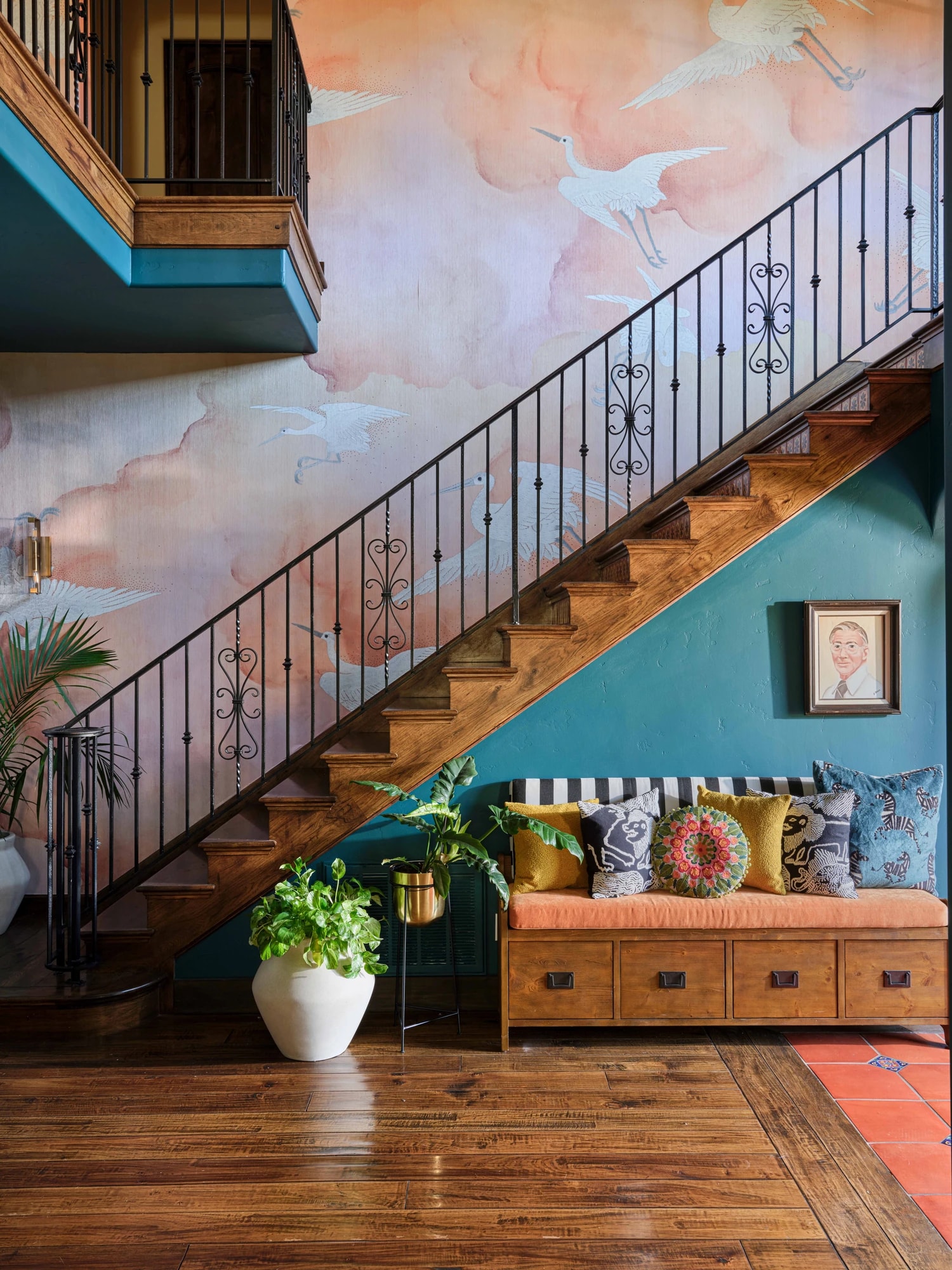 The staircase against a painted mural of clouds and cranes, with a cushioned bench below