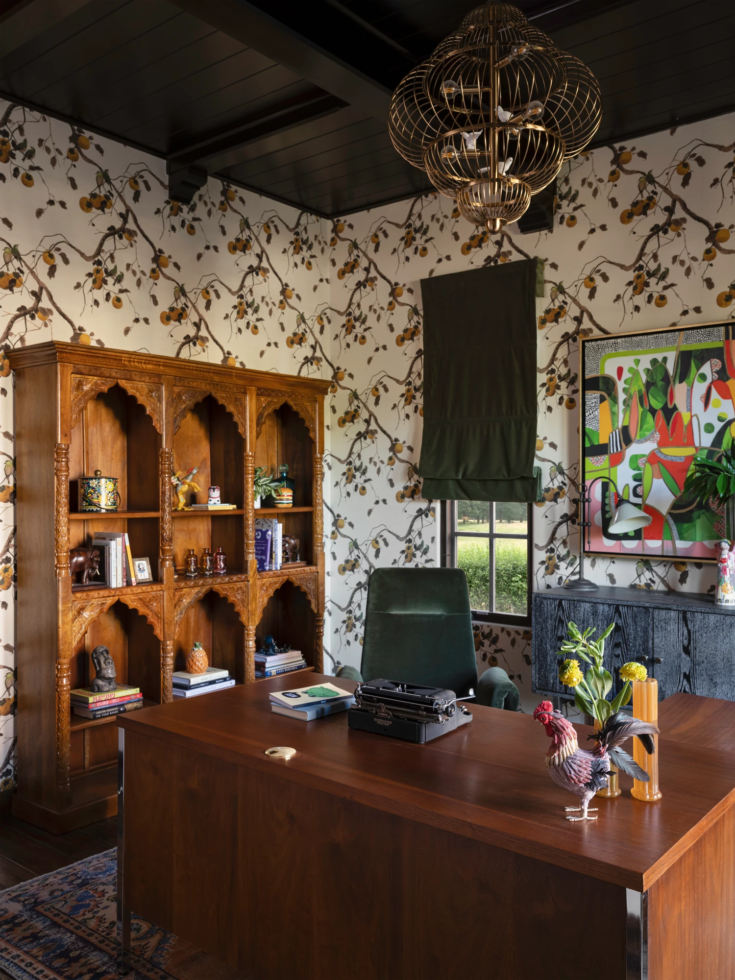 The arched wooden bookcase and desk in the botanical-papered study