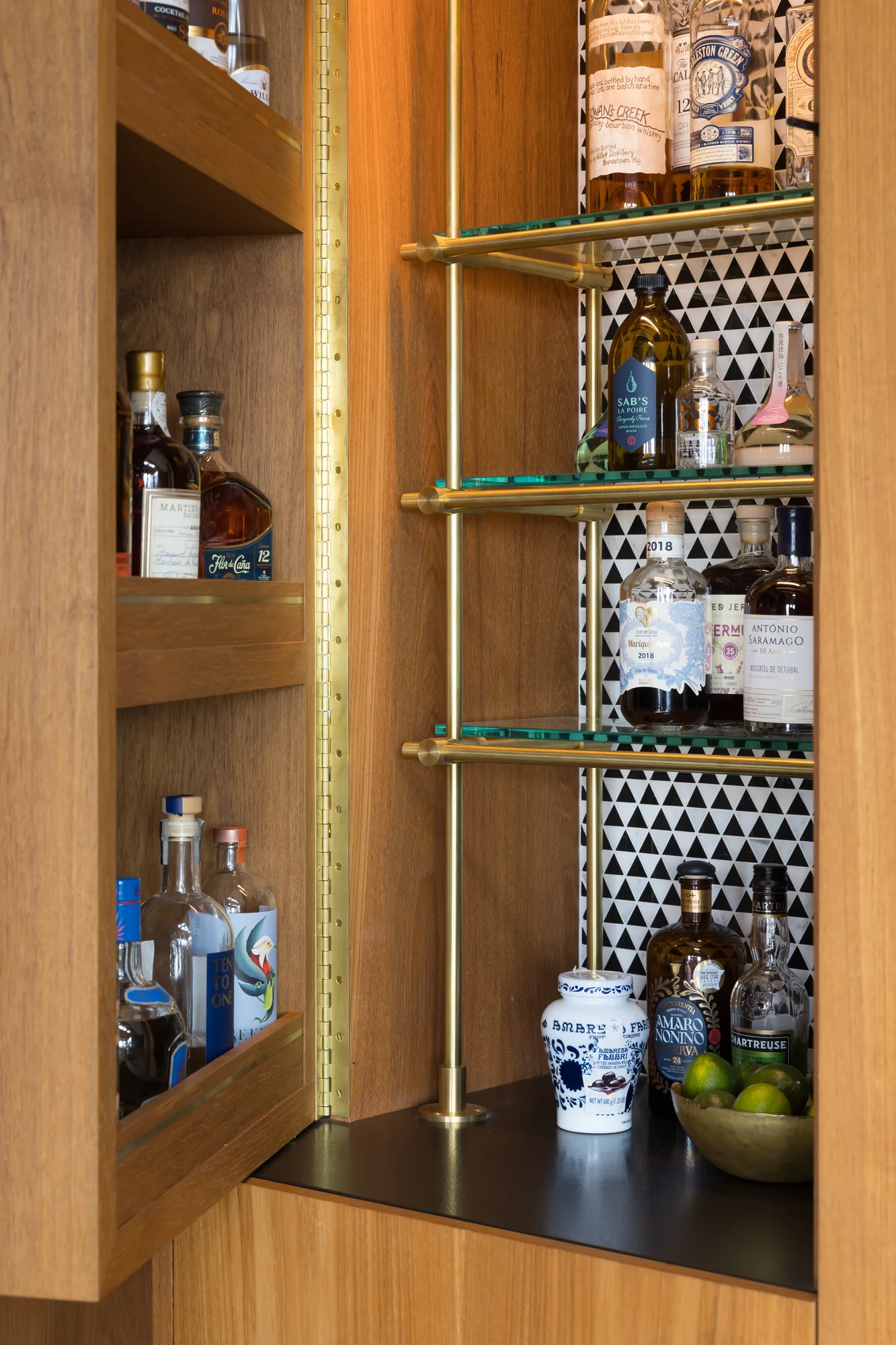 Open bar cabinet with brass shelves against patterned tile