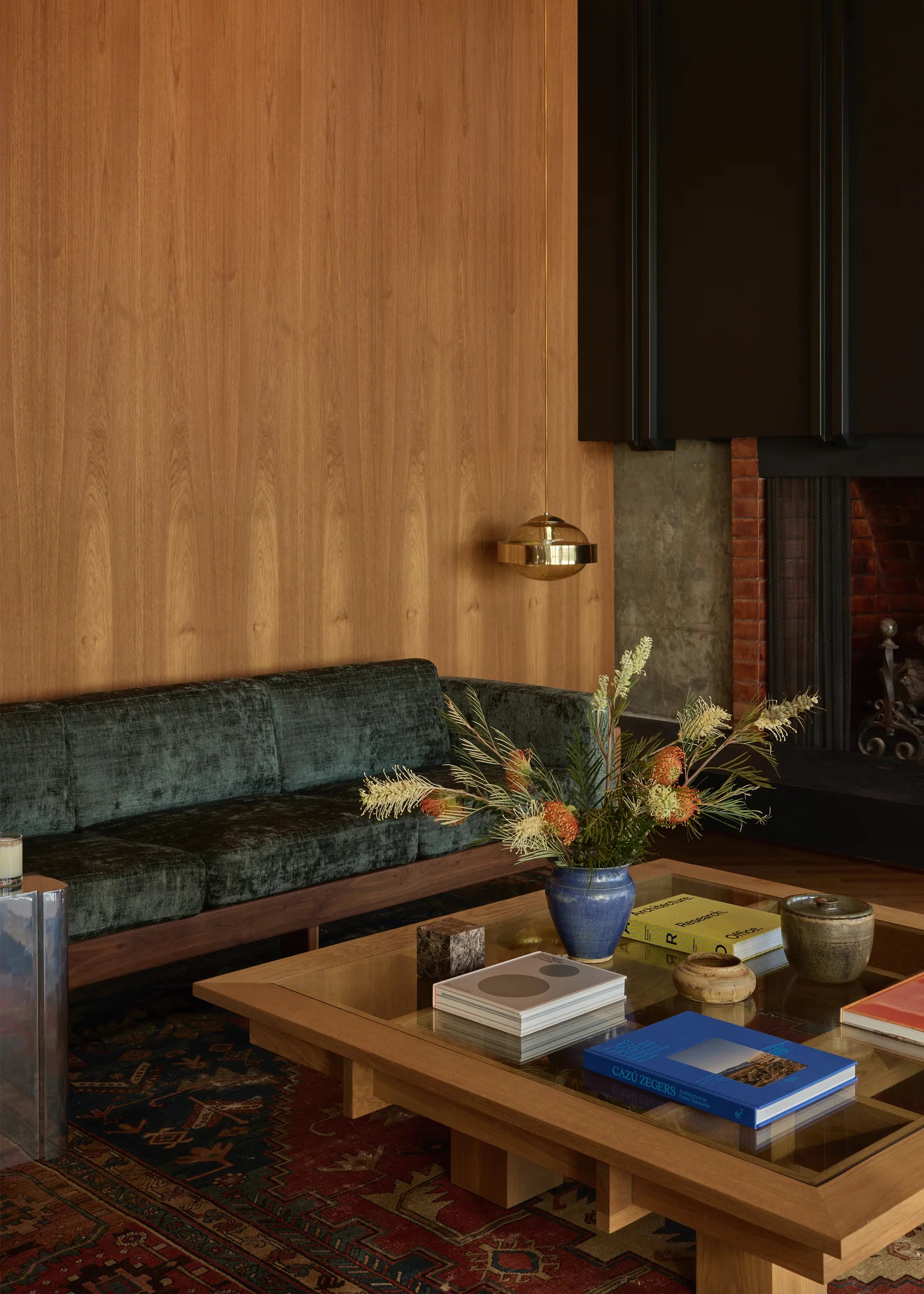 Low wood coffee table stacked with books over a patterned rug