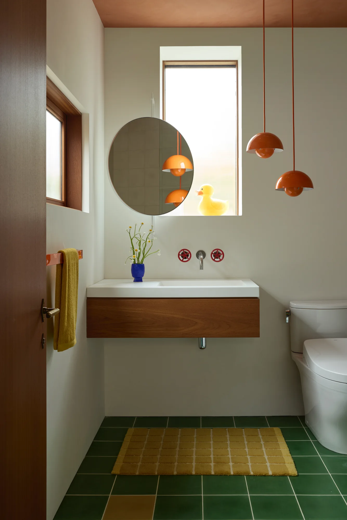 Powder room with orange pendant lights over a green tile floor