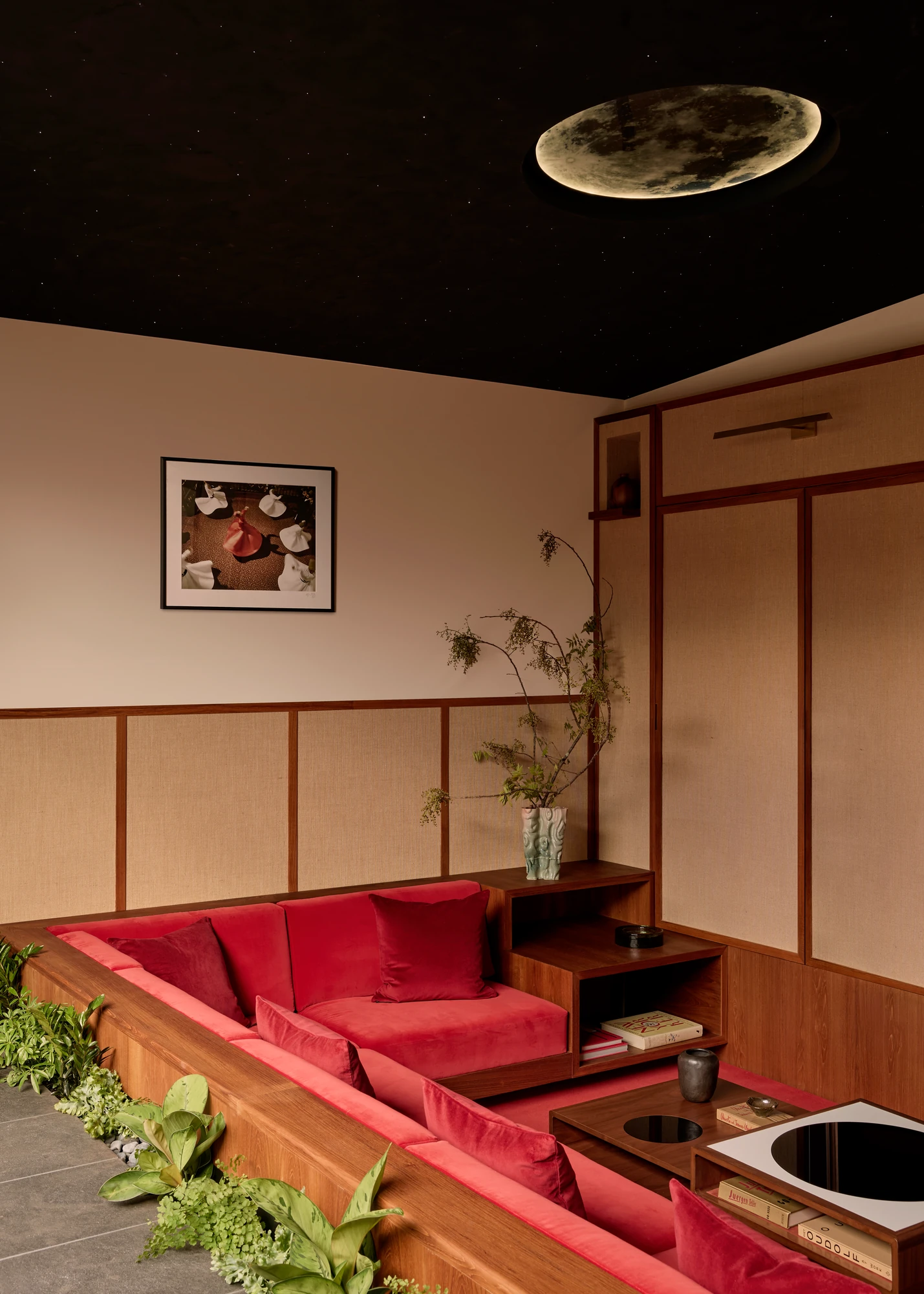 Long red built-in banquette under a framed print in a wood-lined room