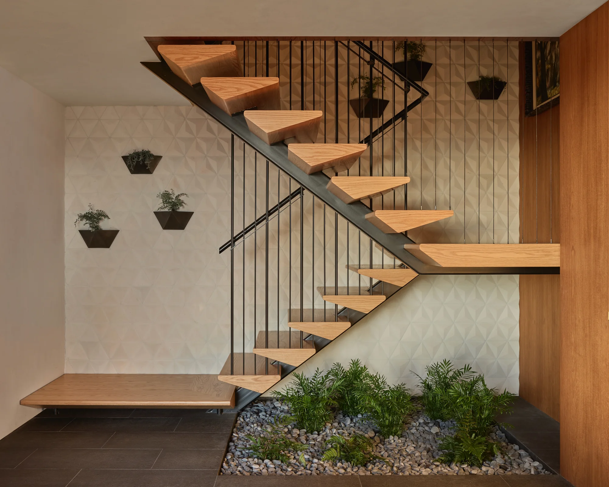 Open-tread stair with wall planters above a pebble bed