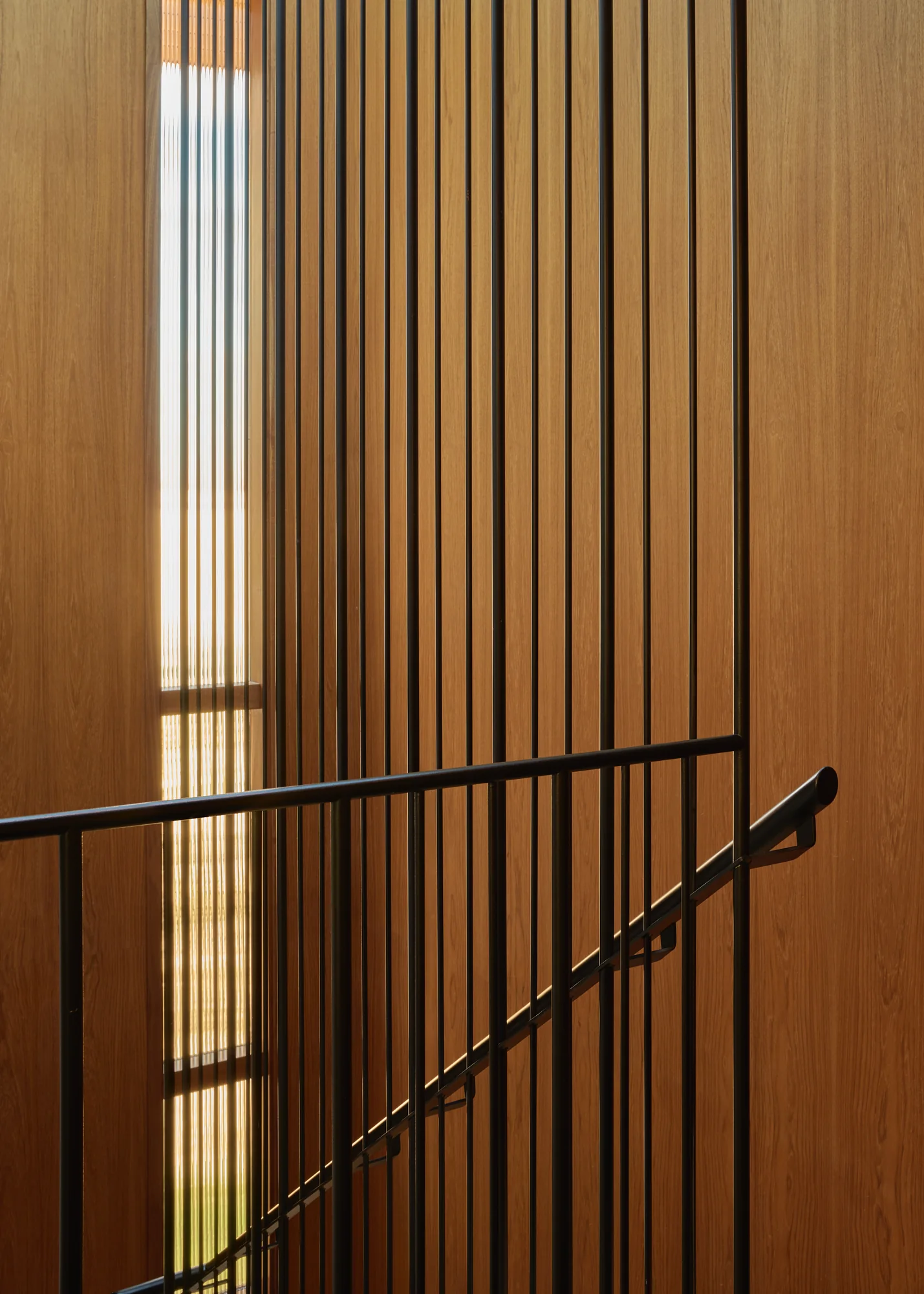 Vertical wood slat screen and black stair rail